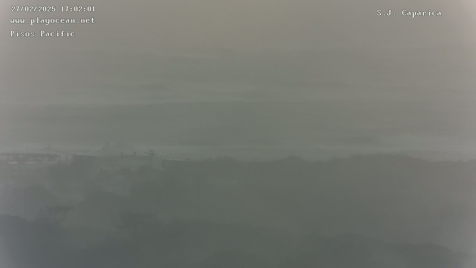 A hazy, foggy landscape shows a distant line of buildings obscured by atmospheric conditions.