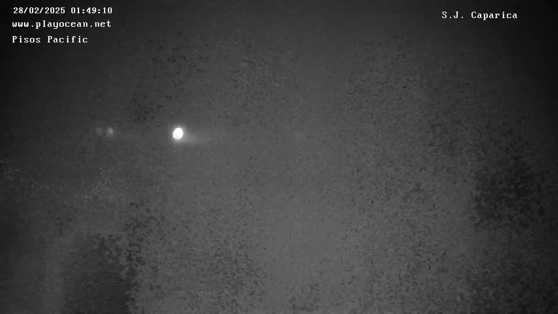 A bright light shines in the night sky, which is mostly dark gray and textured.