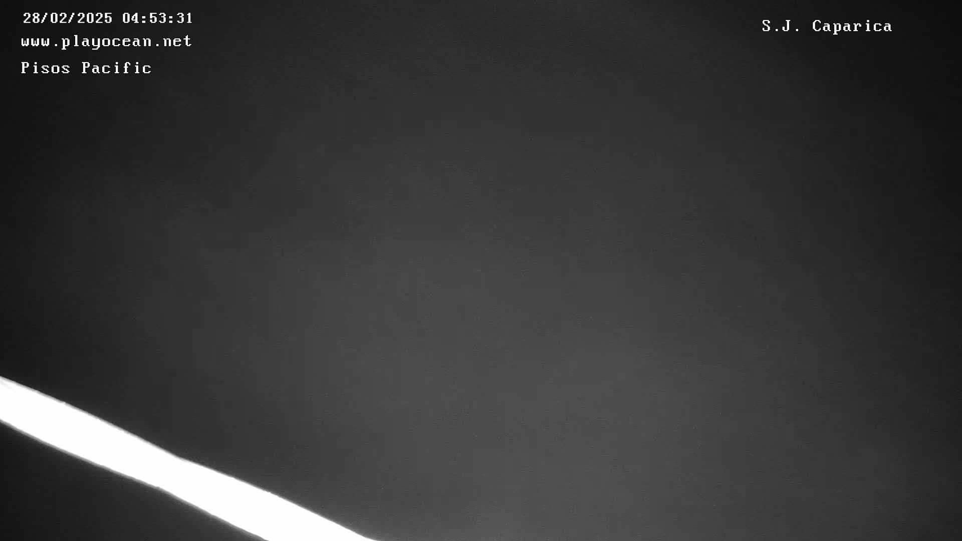 A bright white light streaks diagonally across a dark, nighttime scene.
