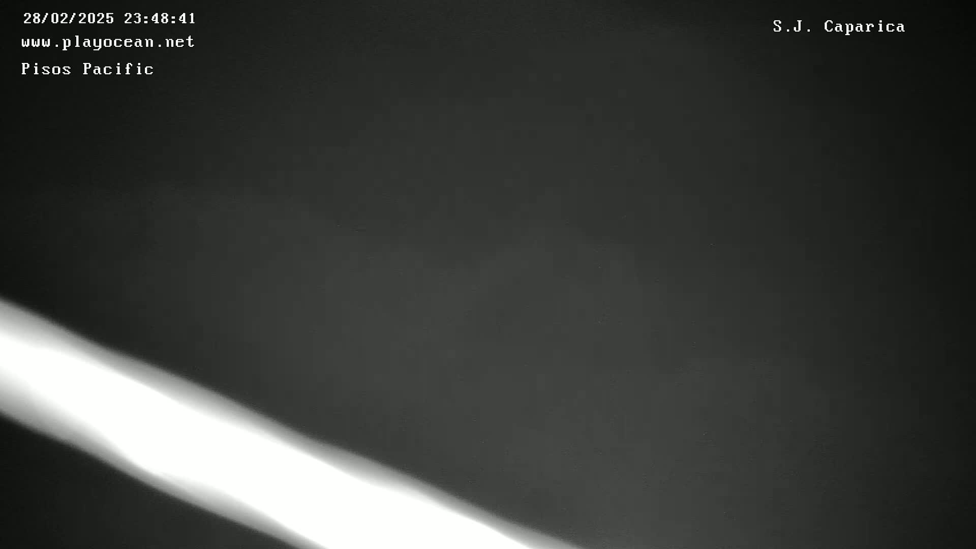 A bright diagonal light streaks across a dark, possibly nighttime, scene.