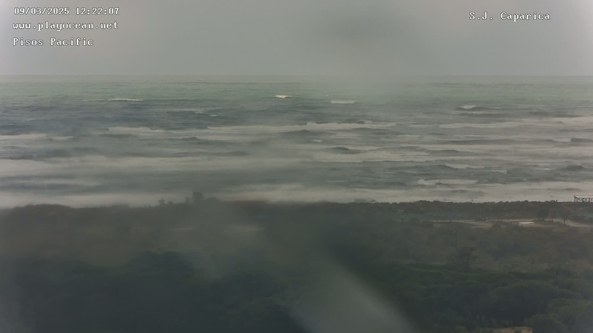 A hazy, overcast day shows a choppy ocean meeting a foggy coastline.