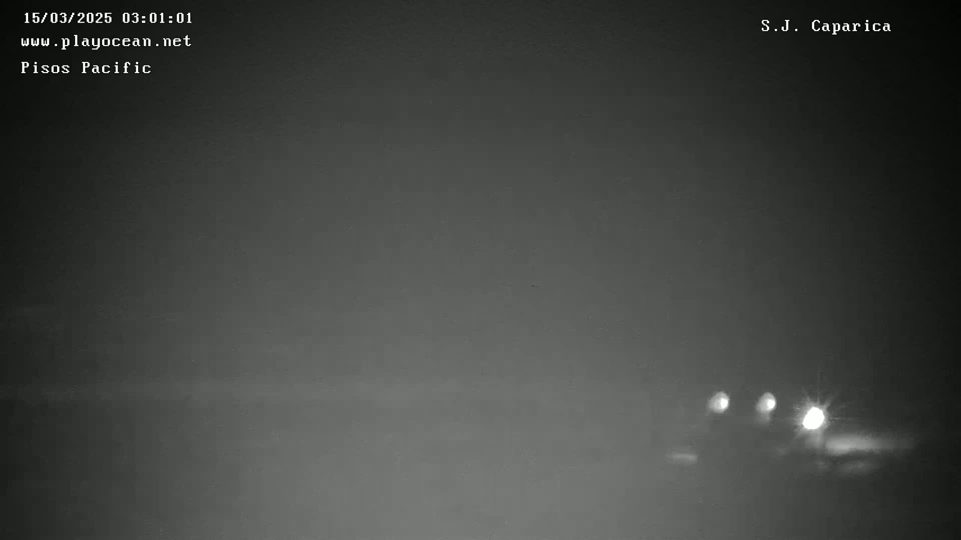 At night in foggy conditions, the headlights of a few vehicles are visible in the distance on a dark road.