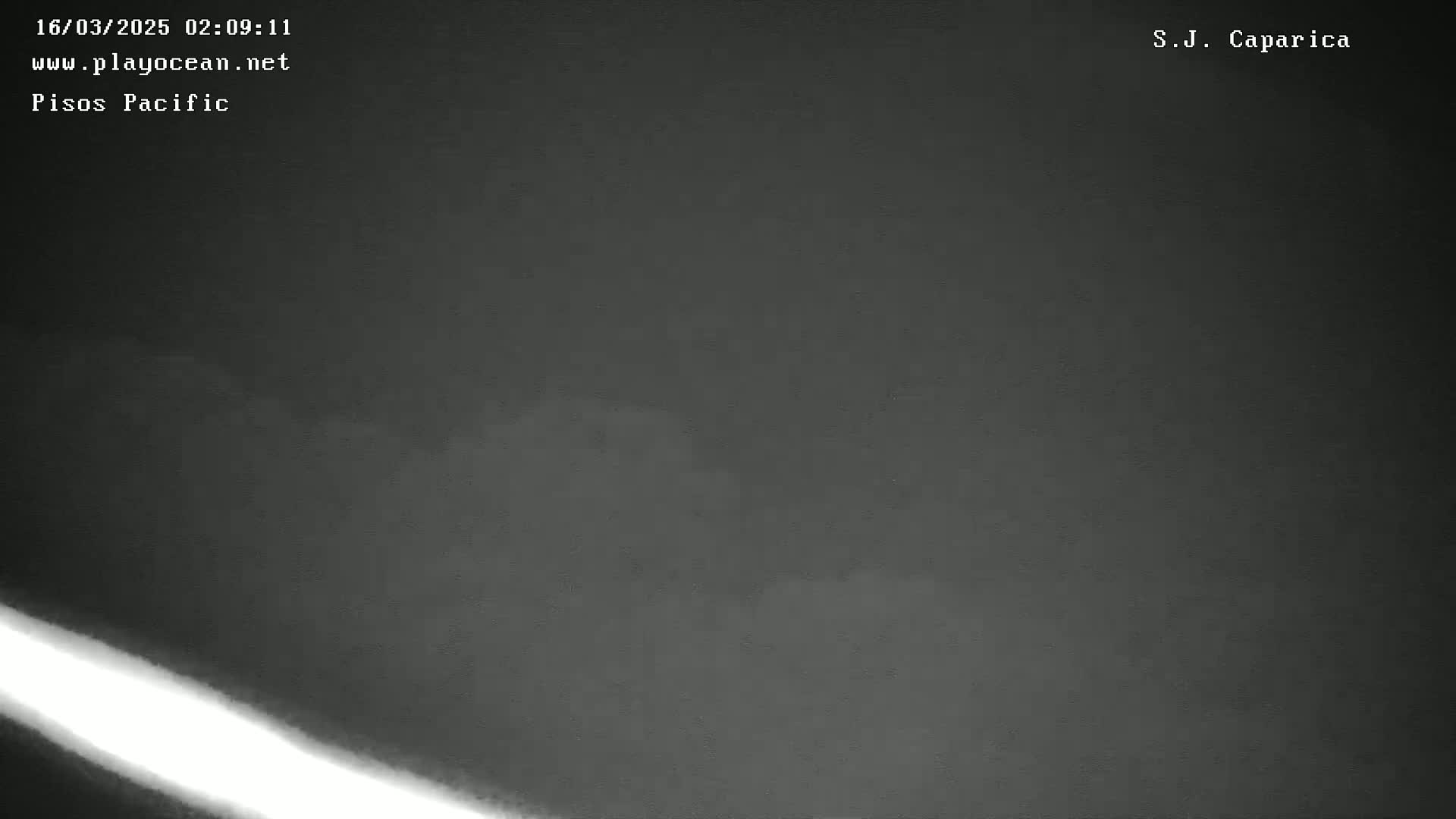 A low-light, nighttime image shows a dark gray sky with faint clouds and a bright streak of light diagonally across the bottom.