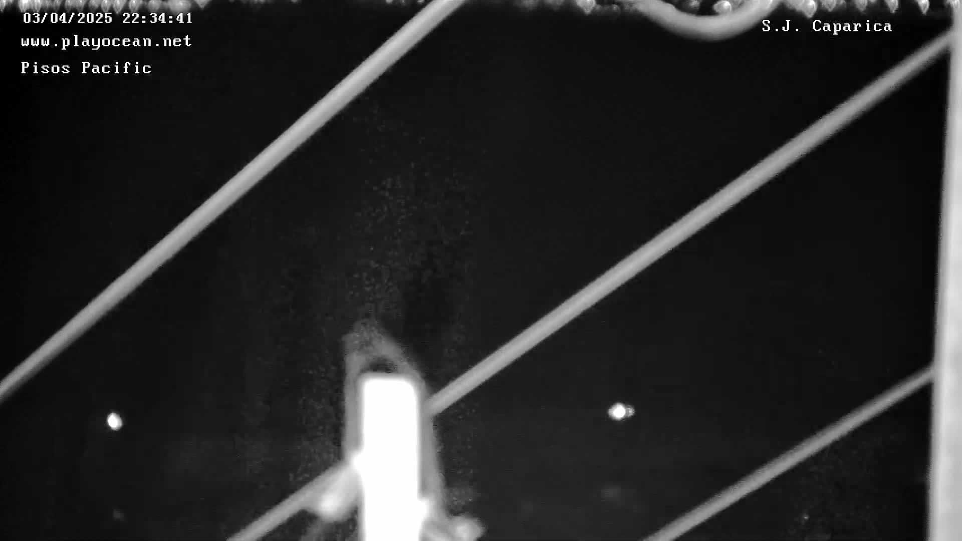 A nighttime, low-light image shows bright diagonal lines intersecting over a dark, grainy background.