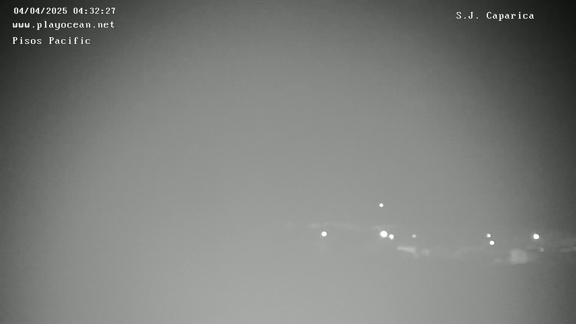 A hazy, dark gray nighttime scene shows a few distant lights on the horizon.