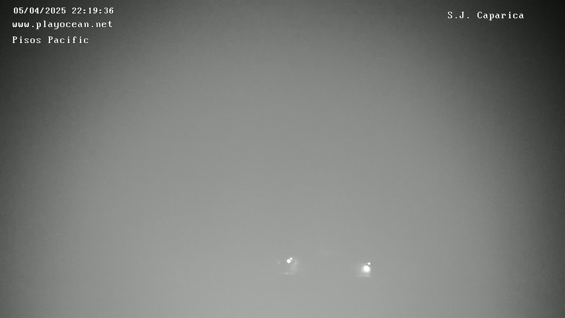 A foggy, nighttime scene shows two faint lights in the distance.
