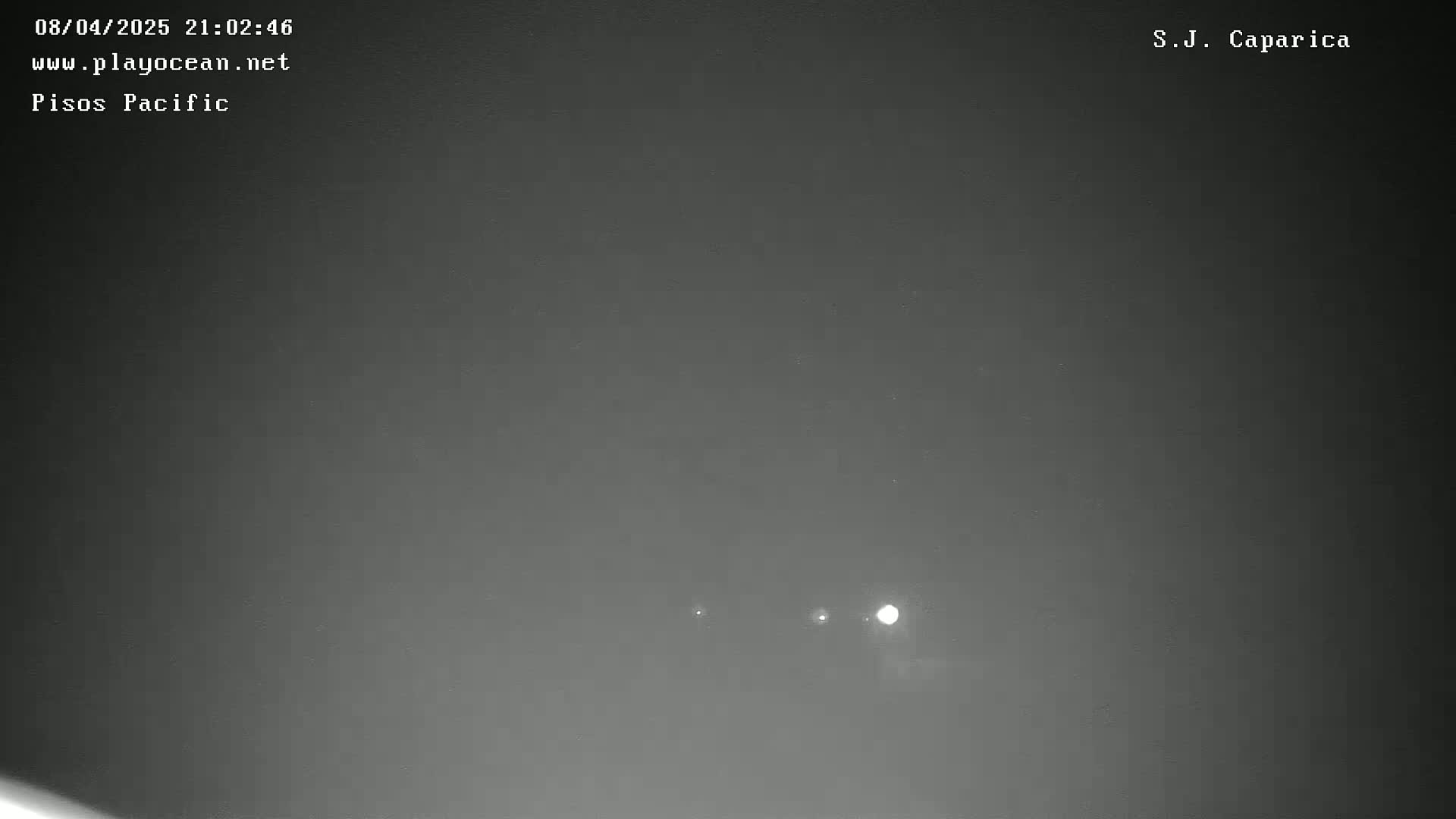 A nighttime, overcast sky shows three bright lights in the distance.