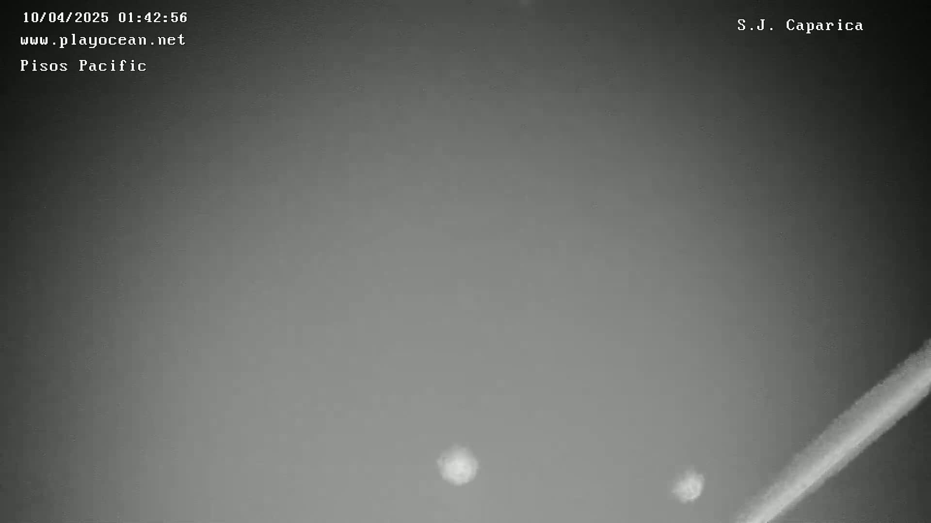 A nighttime, overcast sky shows two faint lights and a diagonal streak of light.