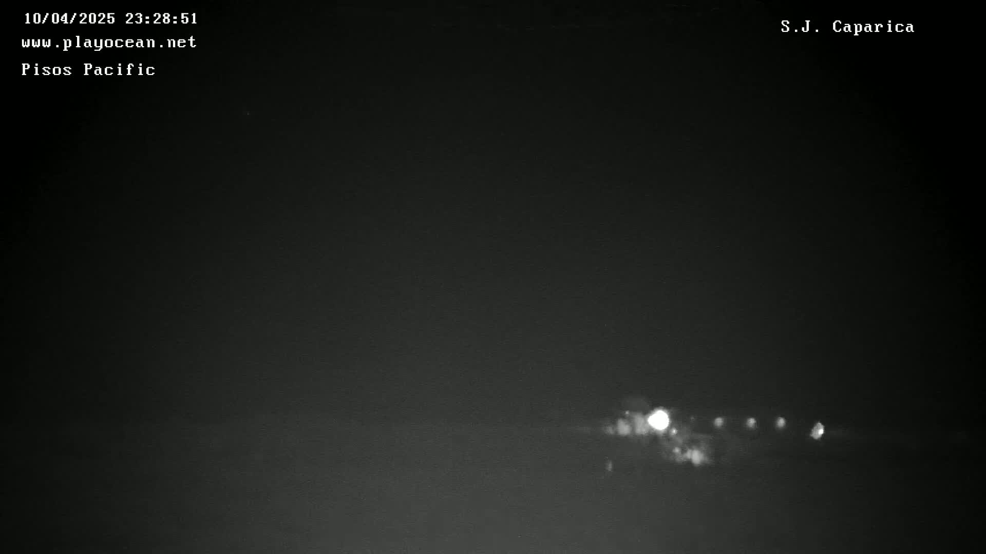 A low-light nighttime image shows a line of distant lights on the horizon.