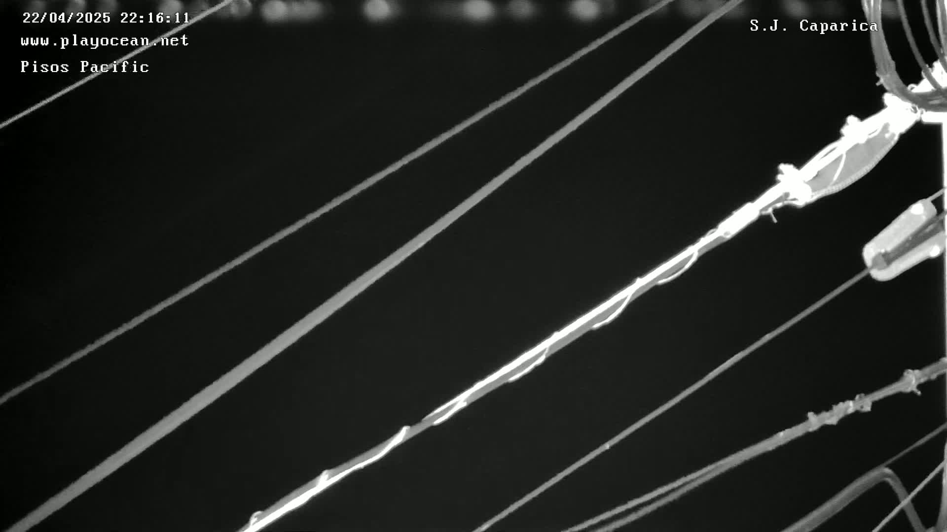 A nighttime, low-angle close-up shows several electrical wires crisscrossing against a dark background.