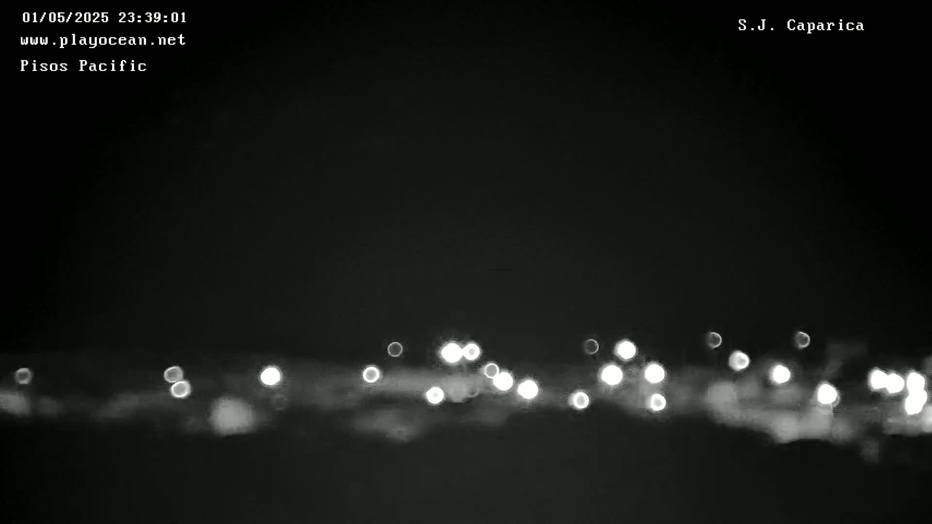At night, a blurry line of lights is visible on a dark, seemingly flat surface.