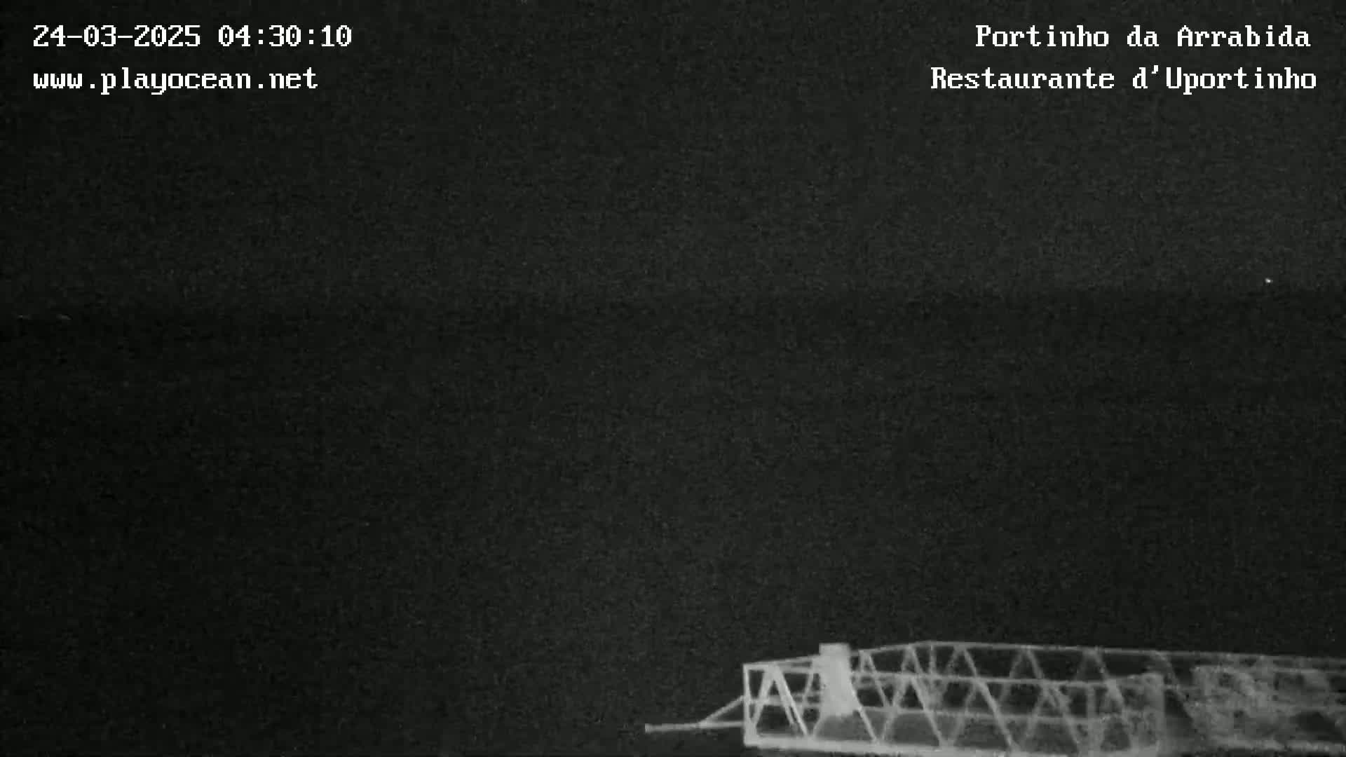 A dark, nighttime image shows a metal structure at the bottom of the frame against a mostly black sky.