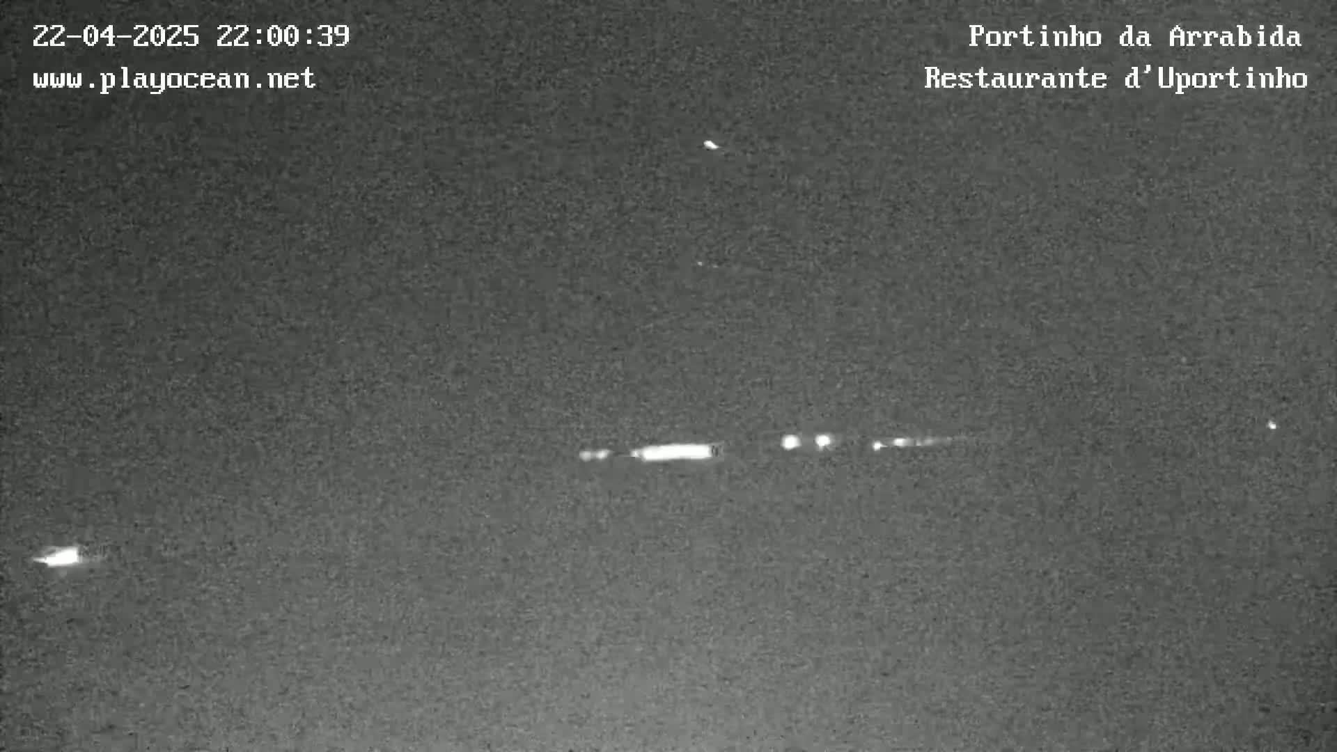 A nighttime, low-light image shows a dark, possibly overcast sky with several small, distant lights, possibly from vehicles or ships.