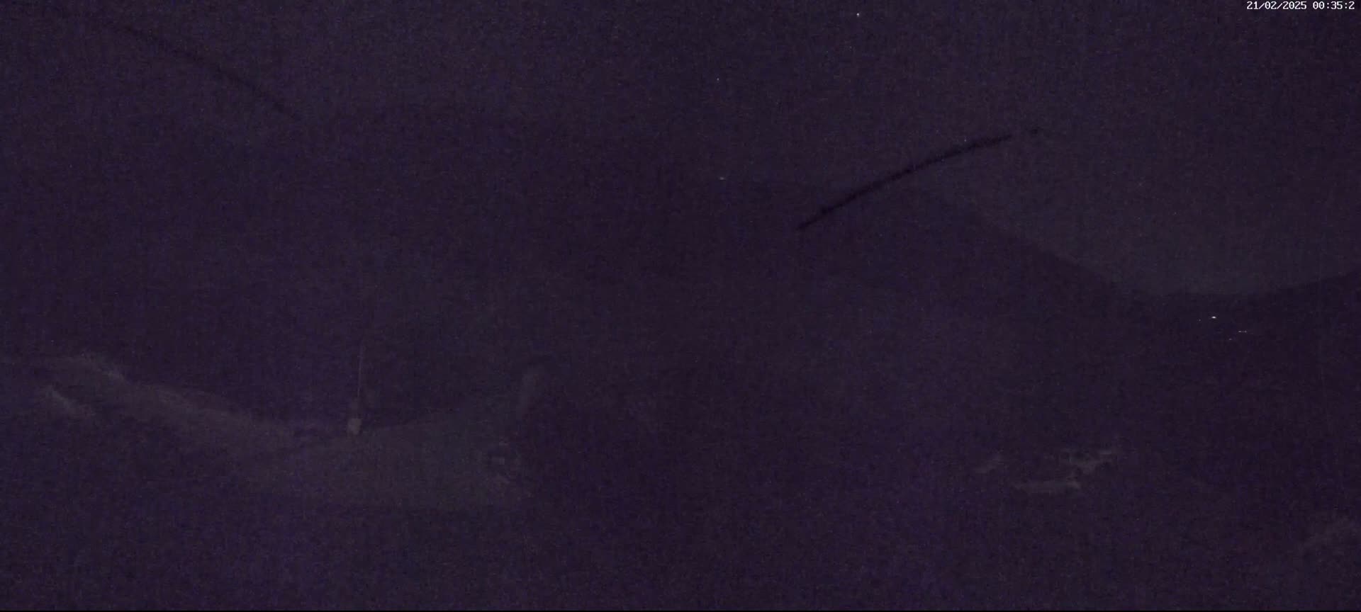 A dark, nighttime view of a landscape with faint lights in the distance.