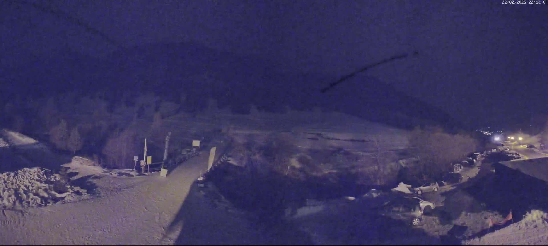 A snow-covered road and parking lot are visible at night under a dark sky.