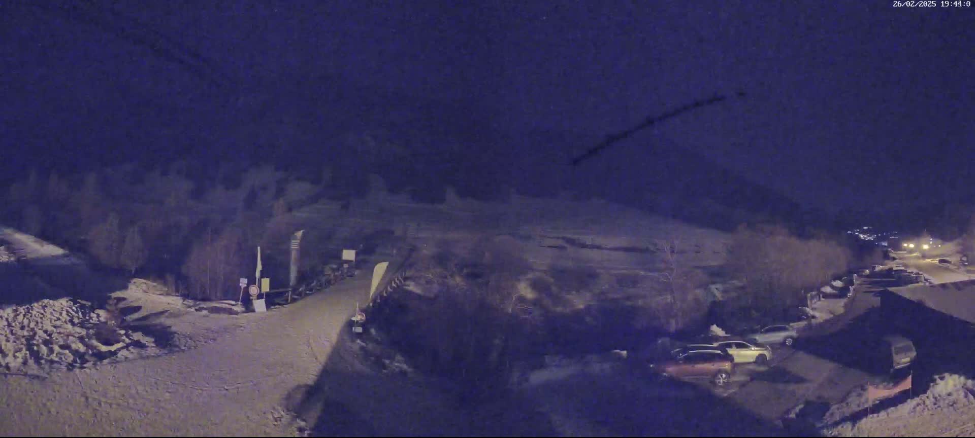 A nighttime, snow-covered parking lot with several cars is visible, and a dark sky with a faint streak across it.