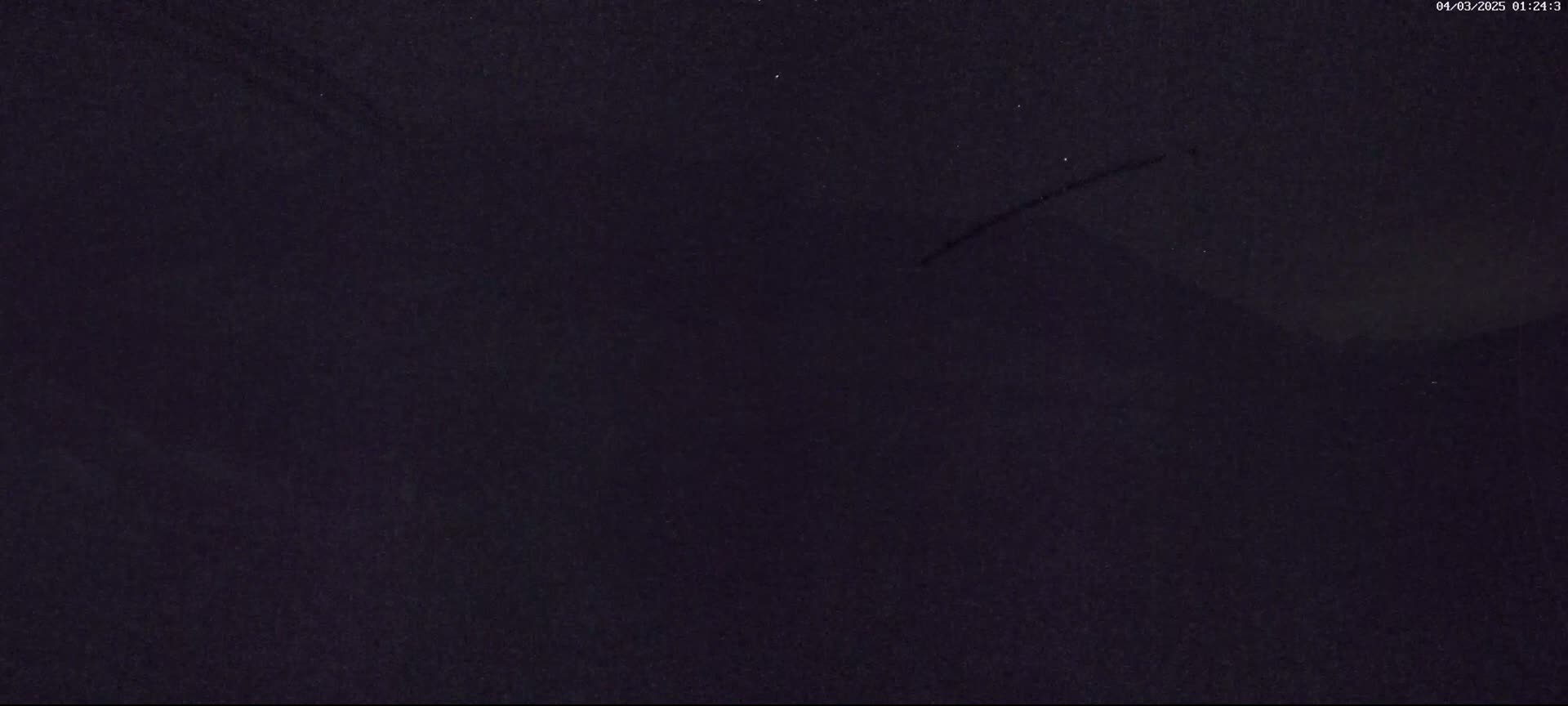 A dark, possibly nighttime, scene shows a mostly featureless, dark-purple sky with a faint, thin streak across it.
