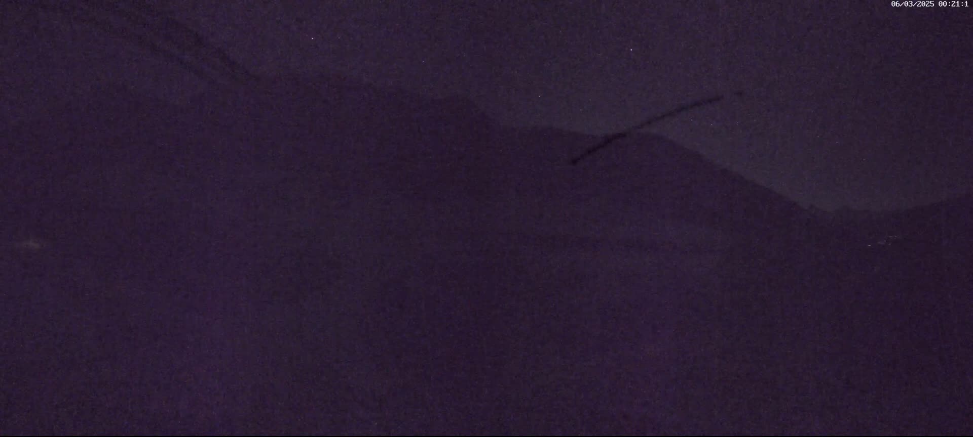 A dark, nighttime image shows a blurry, indistinct landscape under a starless sky.