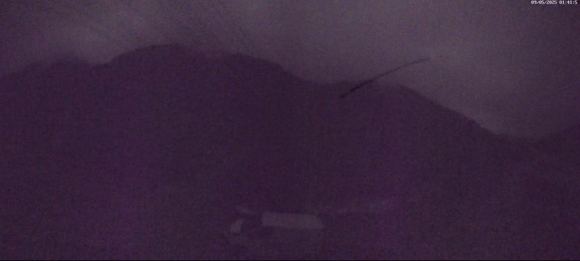 A dark purple, indistinct mass dominates the frame, possibly a pile of material or a shadowed landscape under nighttime conditions.