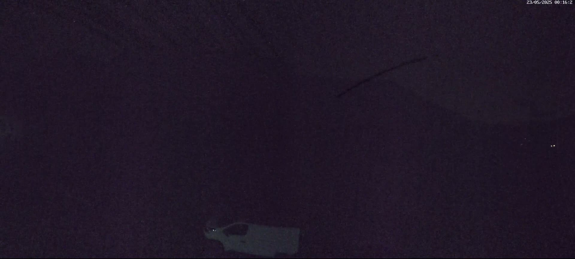 A white van is partially visible in the lower right corner of a dark, nighttime scene.