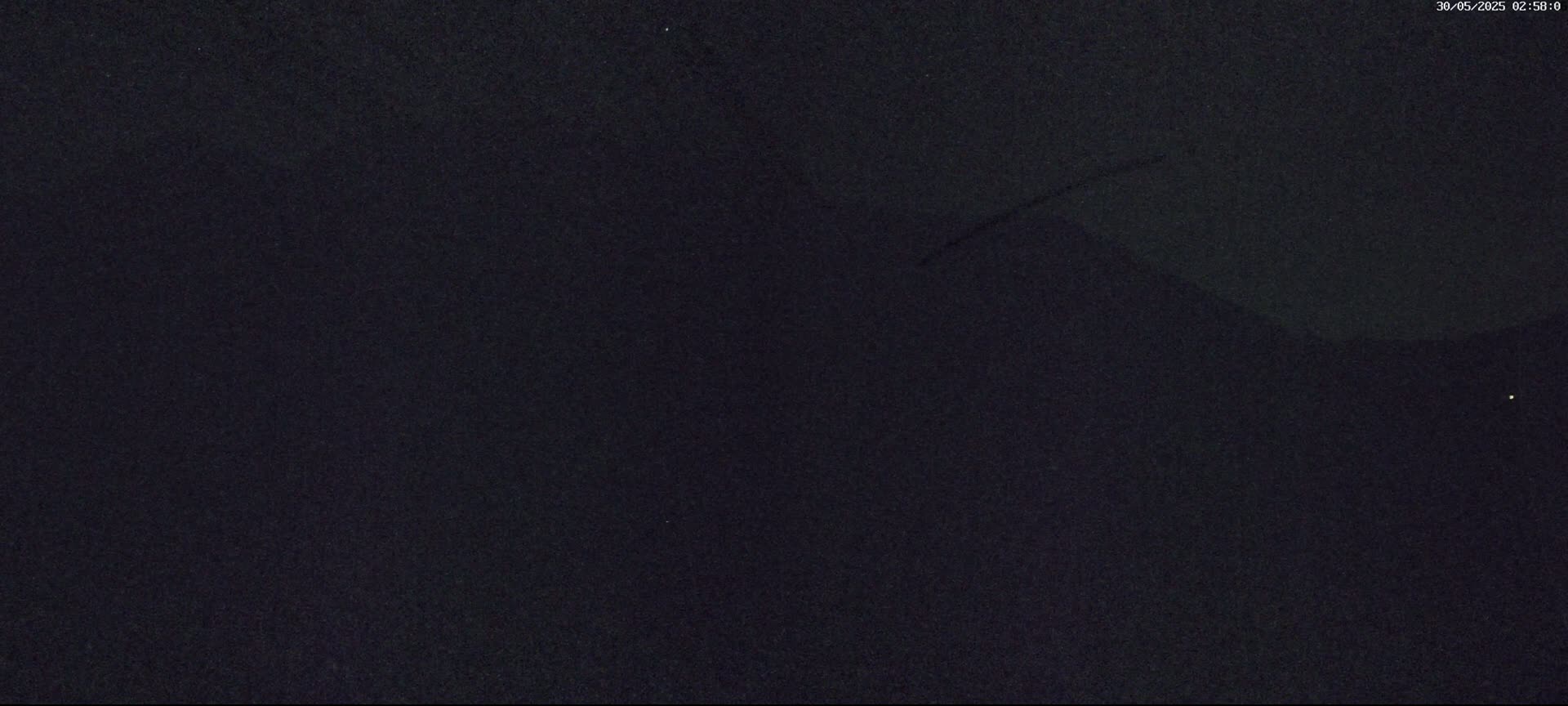 A dark, nighttime outdoor scene shows a mostly clear sky with a few faint, indistinct features.