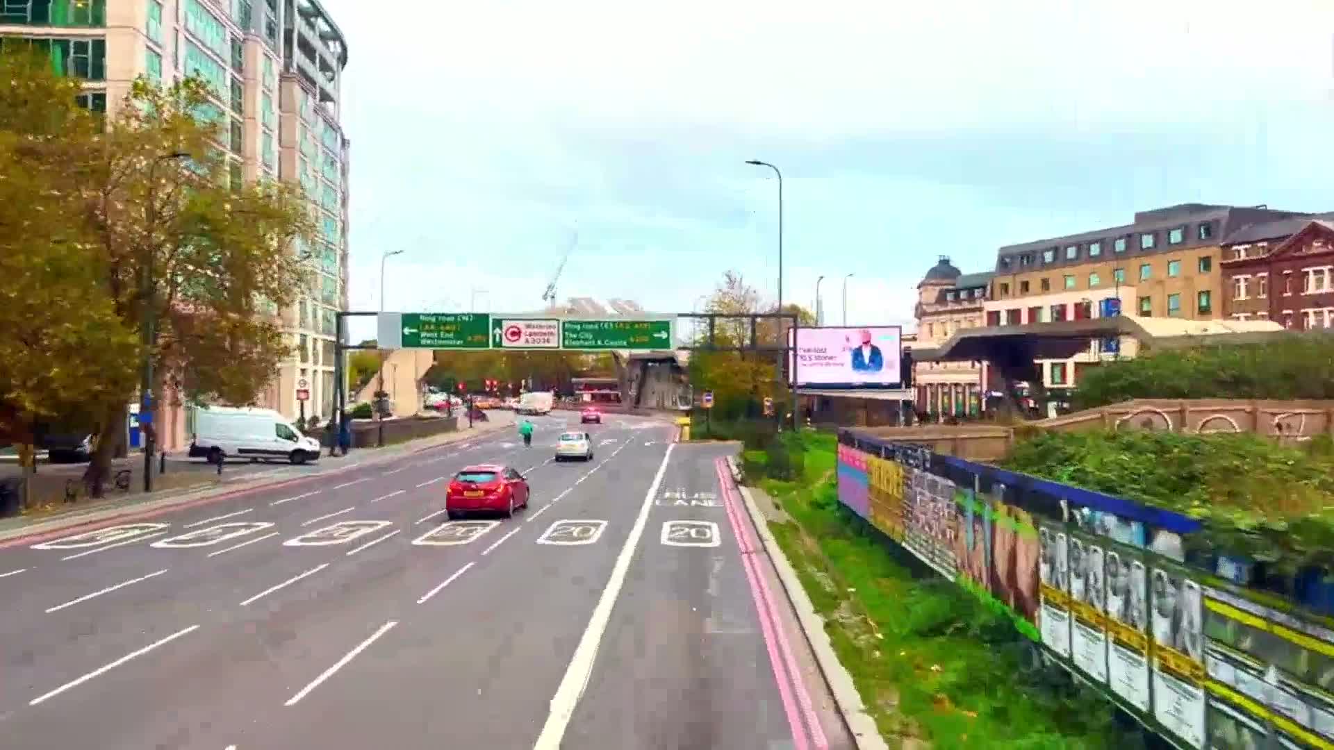 A multi-lane road with several cars, a van, and a building in the background on an overcast day.
