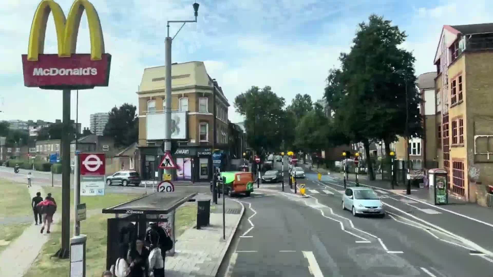 A sunny day shows a street scene with pedestrians, cars, and buildings, including a McDonald's sign and a bus stop.