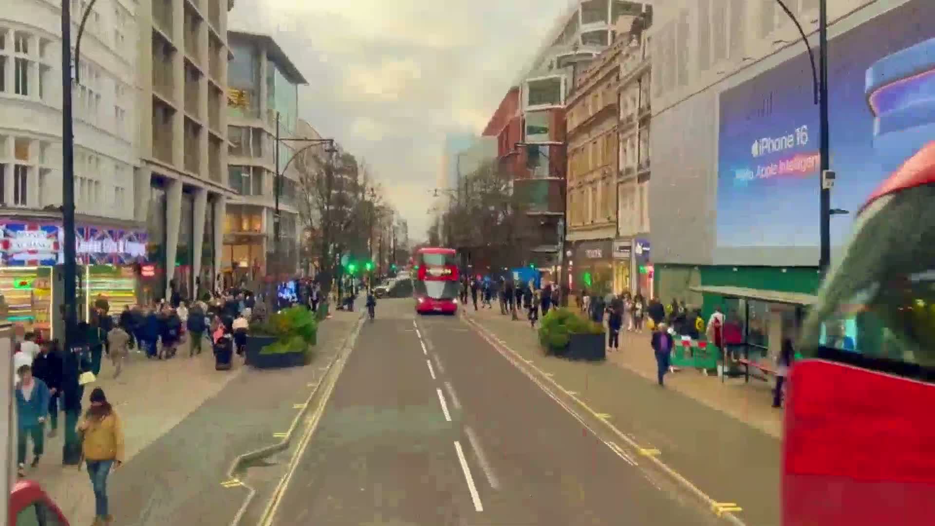 A city street with pedestrians and a double-decker bus, under an overcast sky.