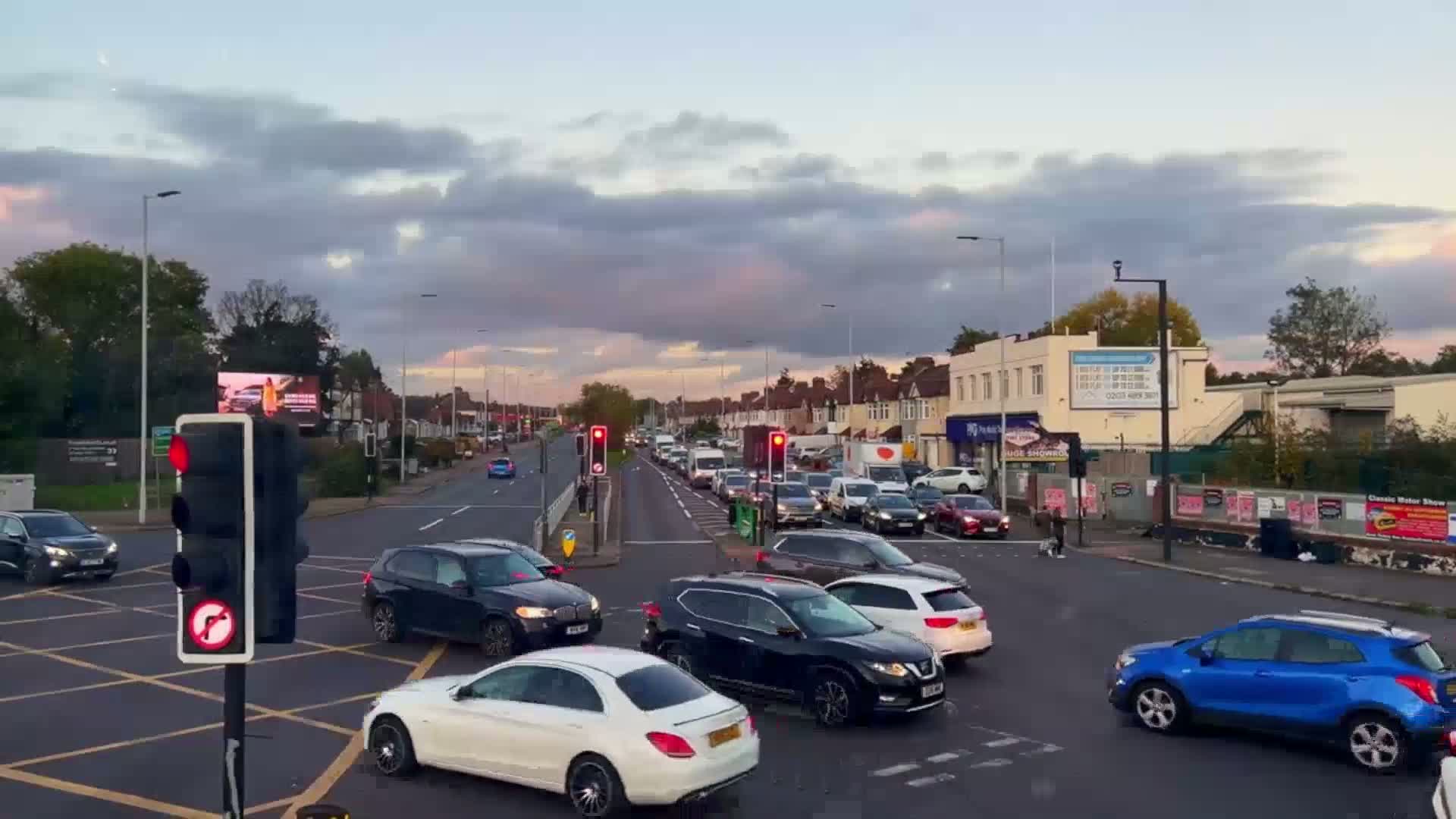 A busy intersection with congested traffic under a cloudy, twilight sky.