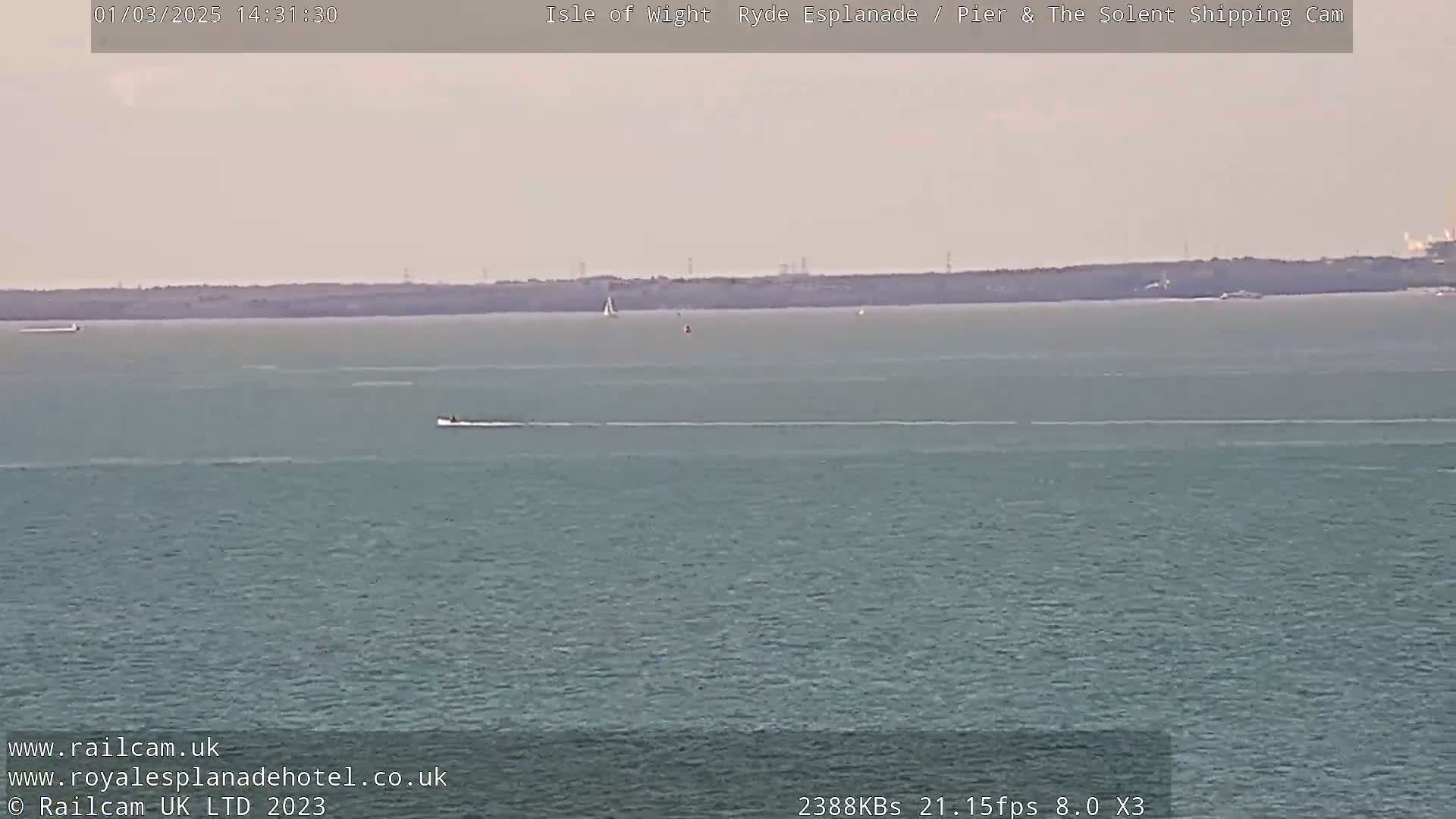 A calm, hazy body of water shows a few small boats and a distant shoreline.