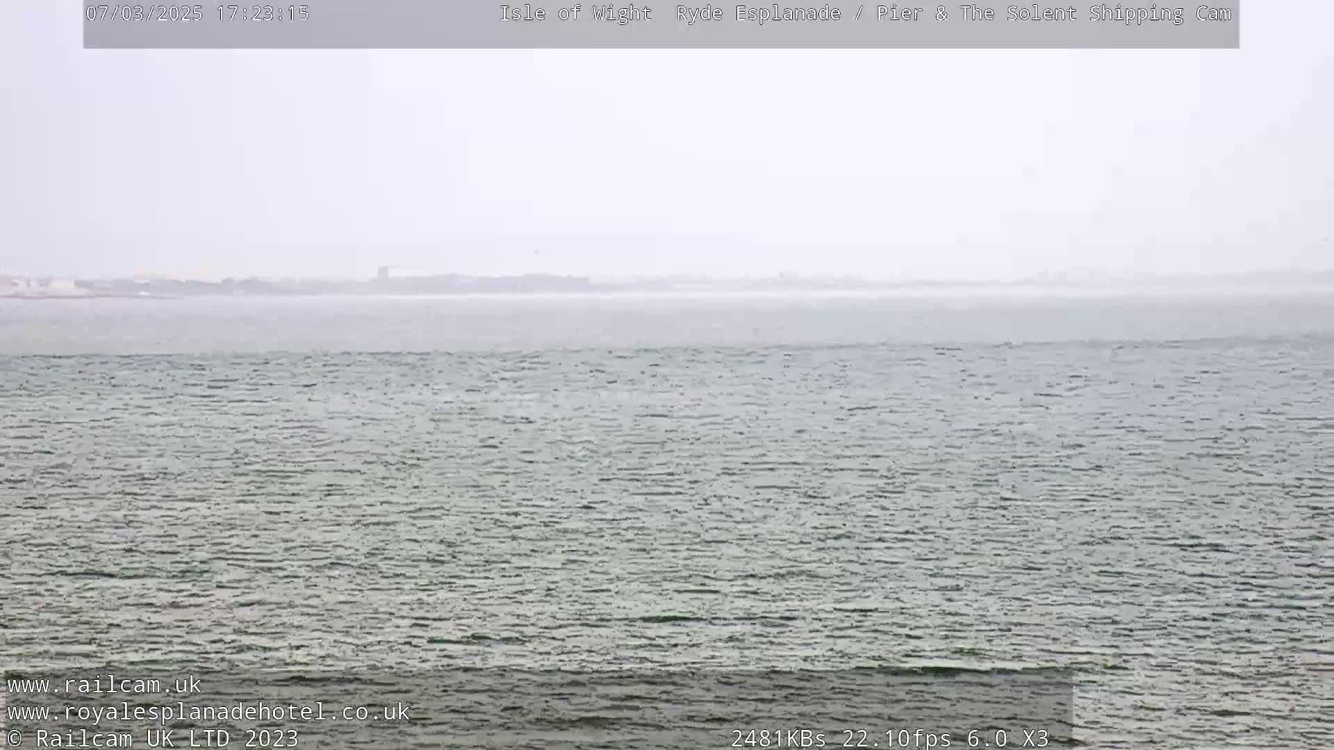 A hazy, overcast view of a calm body of water with a distant shoreline.
