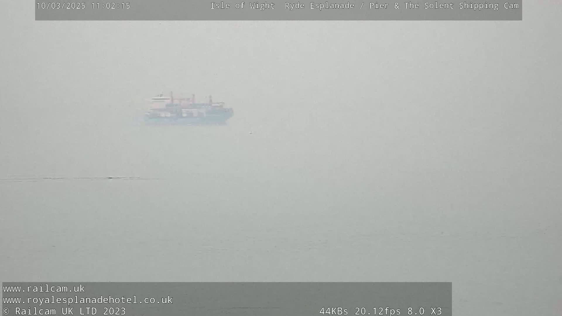 A distant ship is visible on a foggy body of water.