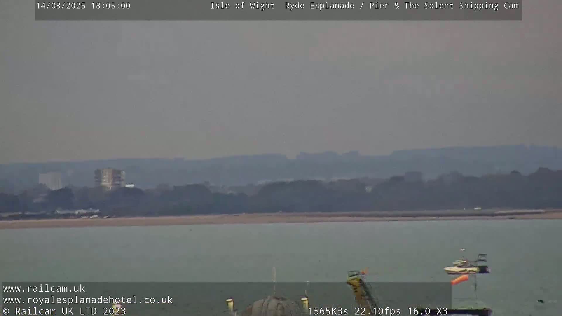 A hazy, overcast view of a body of water with a distant shoreline and a small boat.