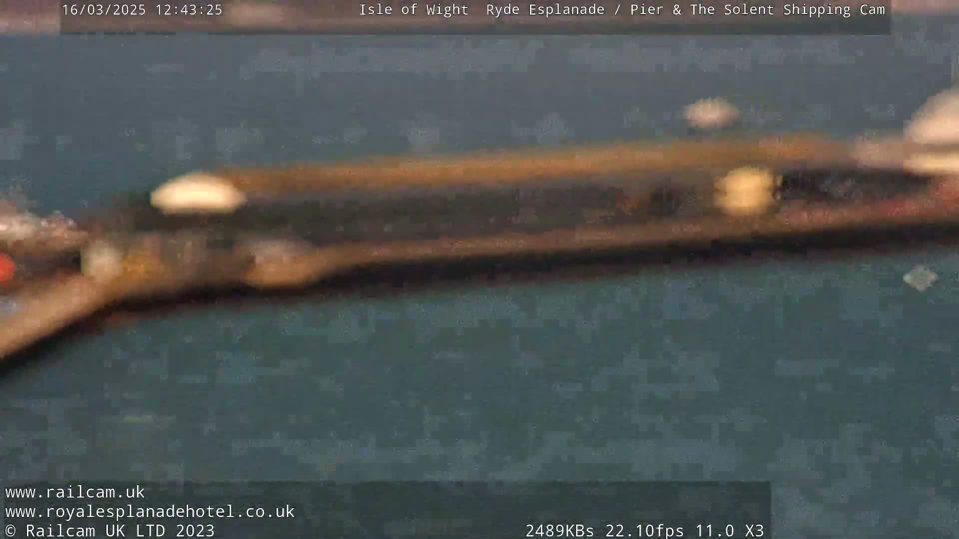 A blurry image shows a dark-colored object moving across a dark-gray surface.