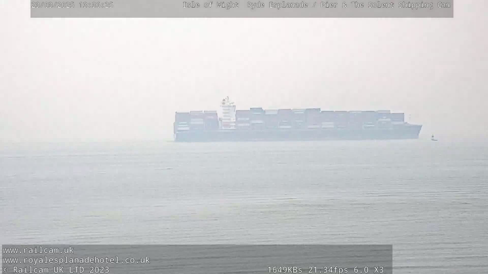 A large container ship is visible on a foggy body of water.