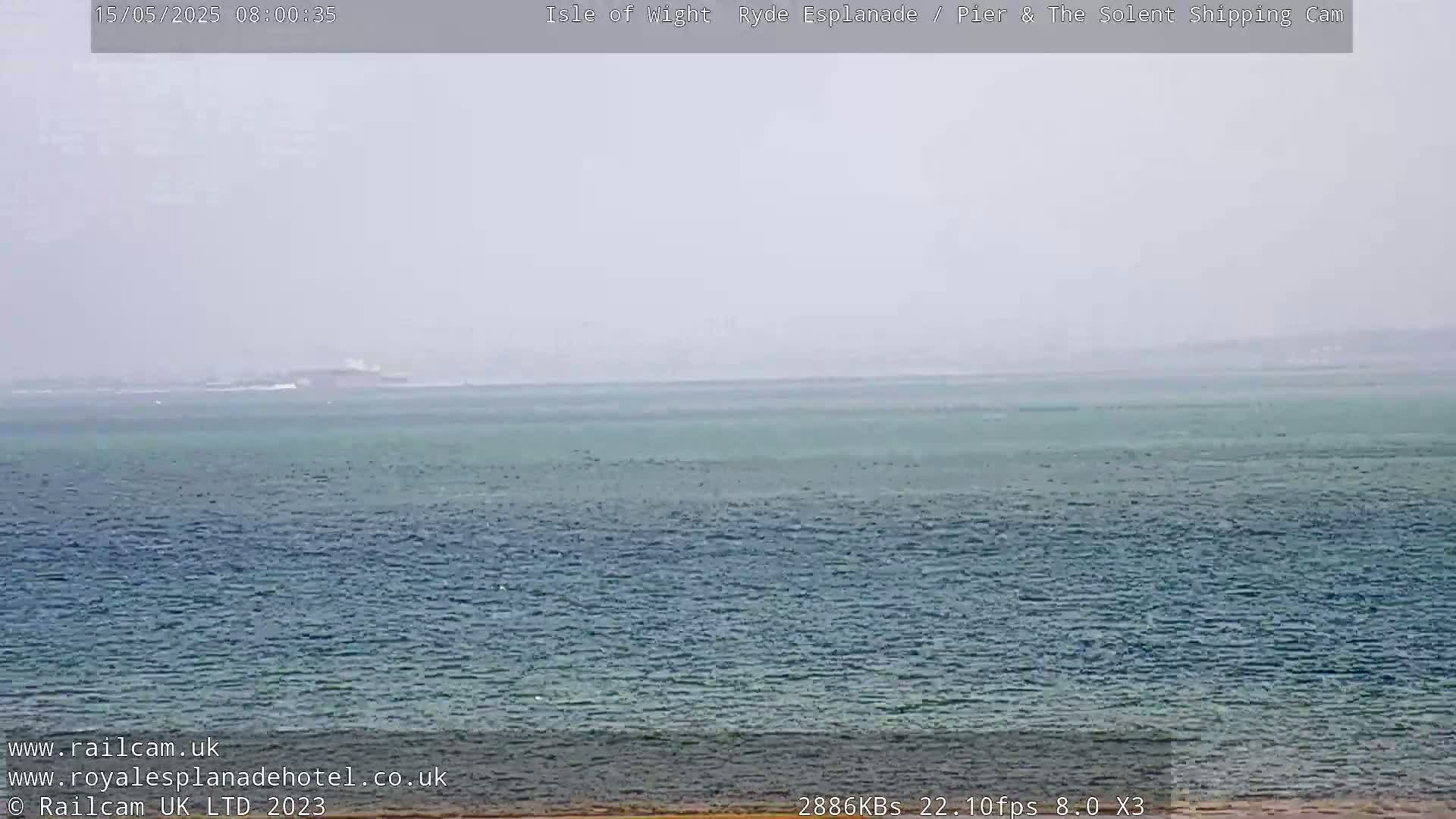 A hazy, overcast view of a calm sea stretches to a distant horizon.