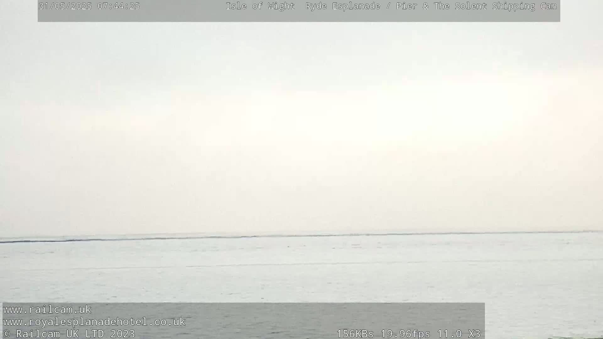 A hazy, overcast day shows a calm body of water extending to the horizon.