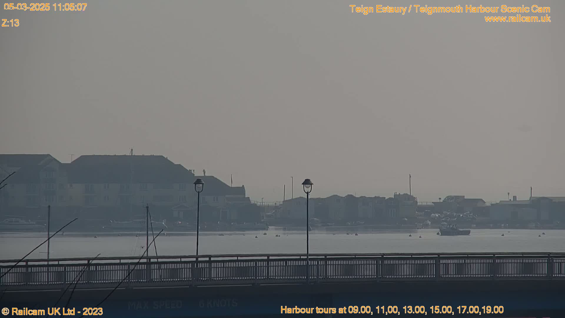 A hazy view of a harbor with buildings and boats in the distance, seen from a bridge.