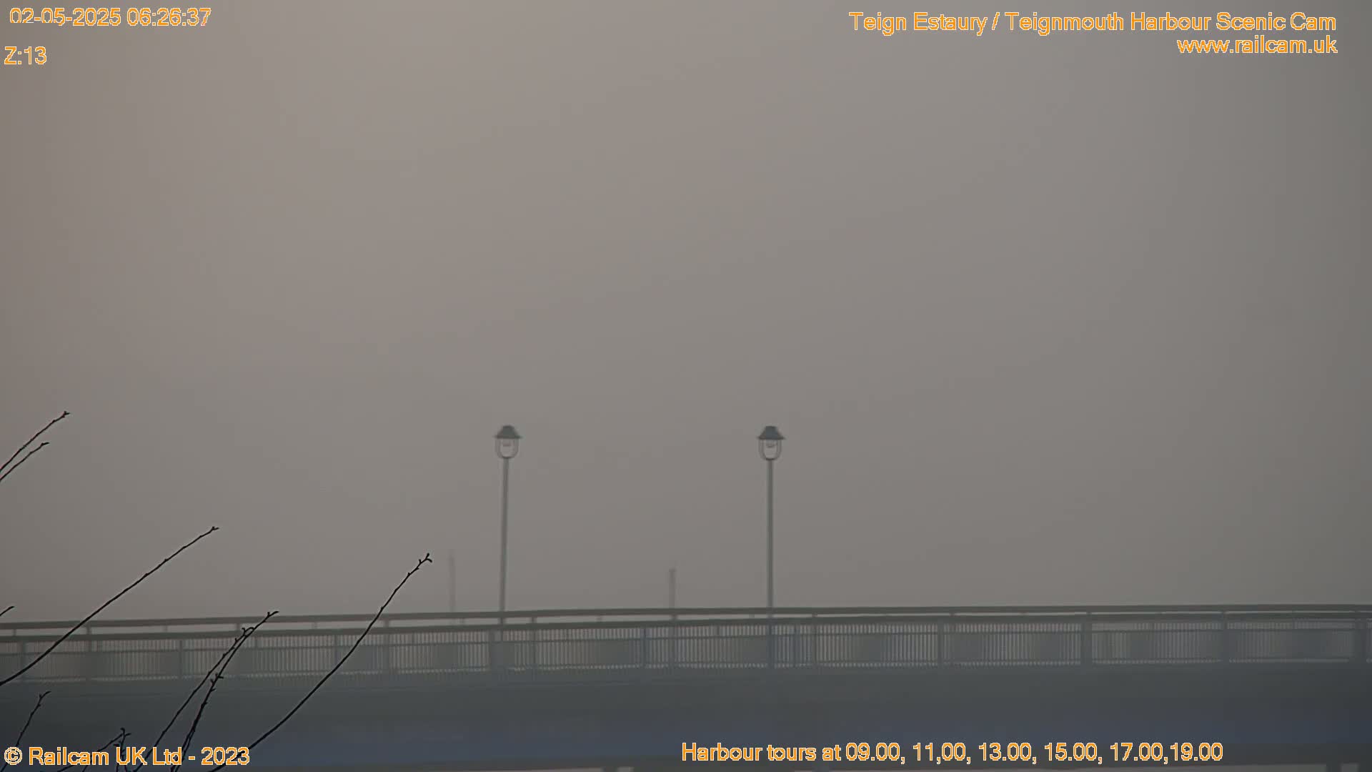 A hazy, foggy scene shows a bridge with two lampposts on it.