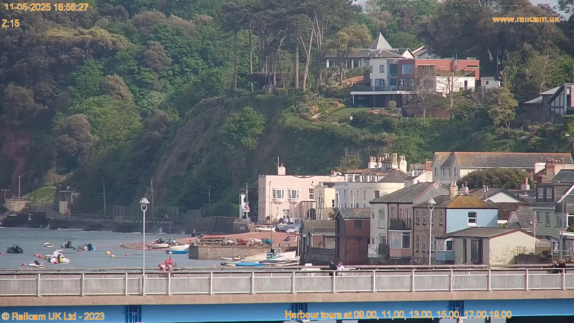 A coastal town with houses and boats on a sunny day, viewed from a bridge.