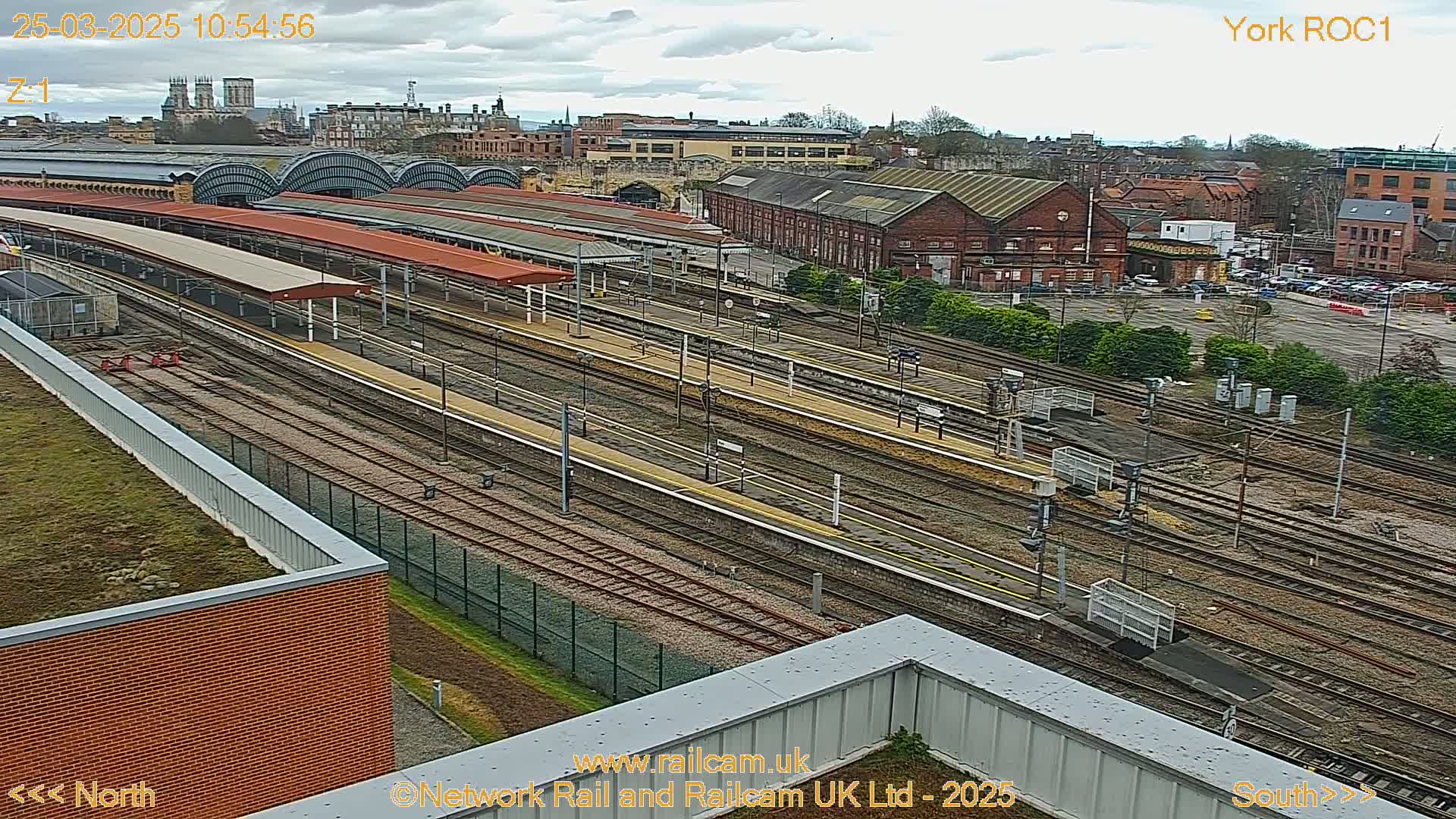 An aerial view of a train station with many tracks and platforms on an overcast day.