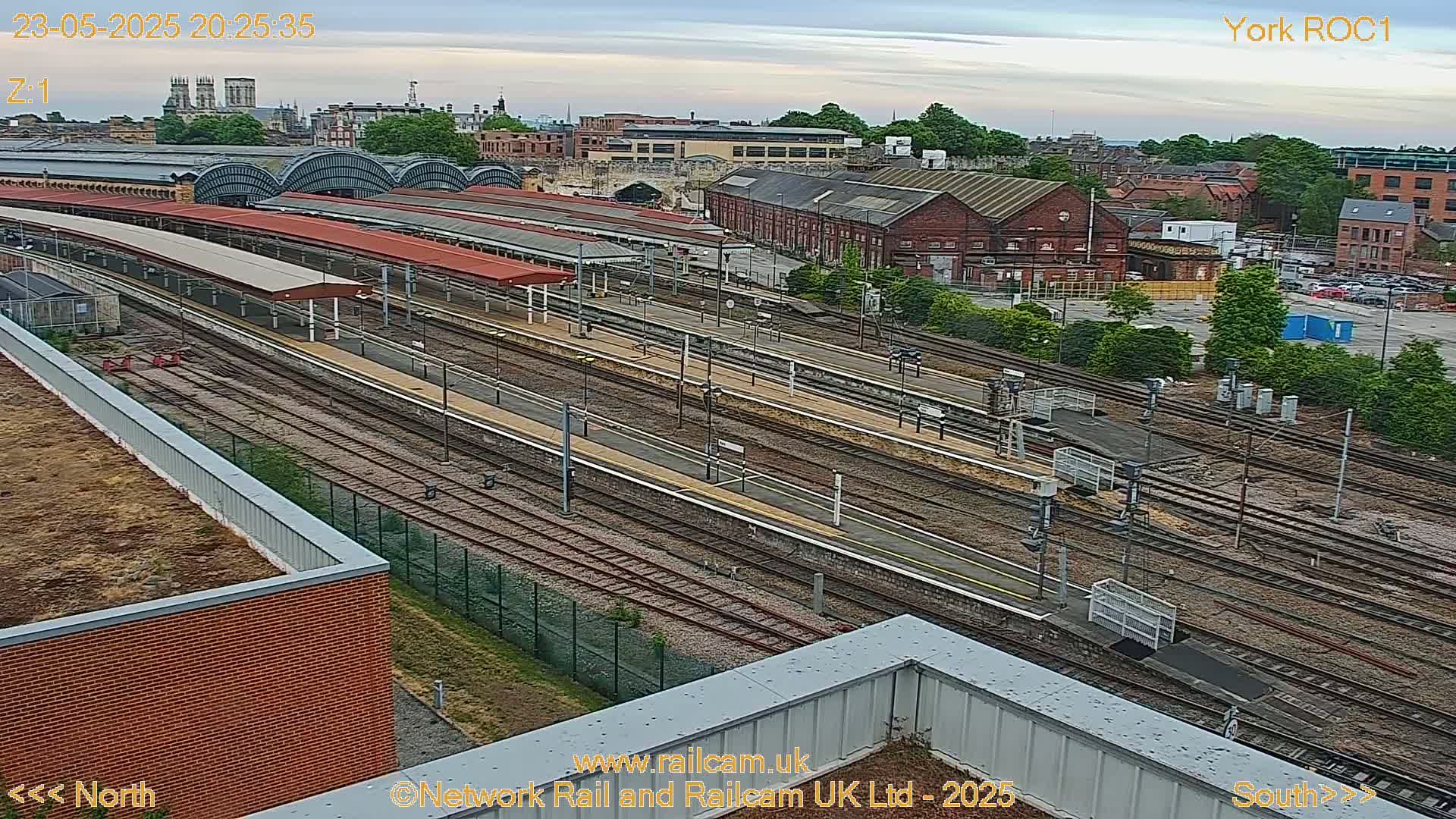 An aerial view of a train station with numerous tracks and platforms under an overcast sky.