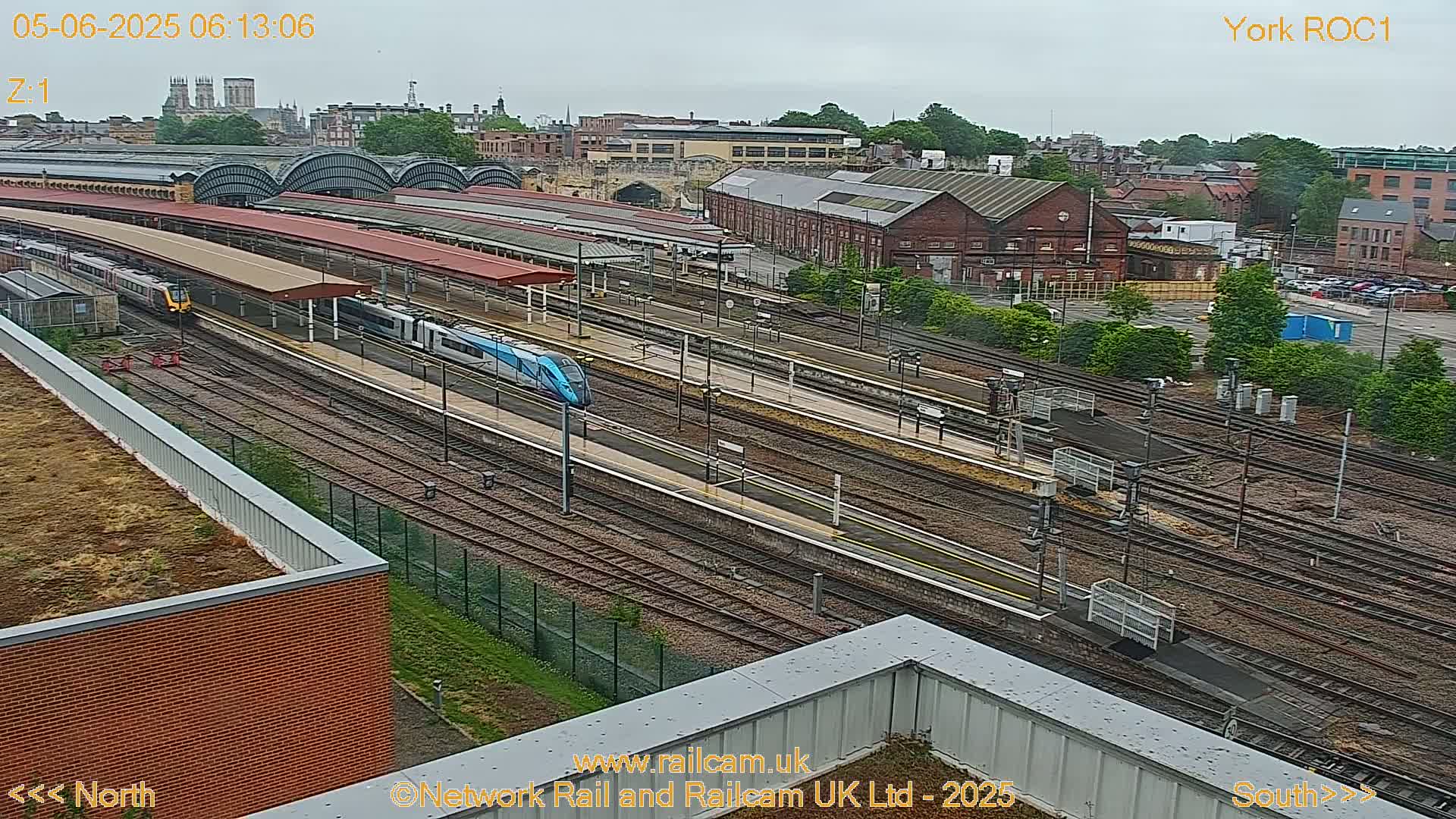 An aerial view of a train station with multiple trains on the tracks under an overcast sky.