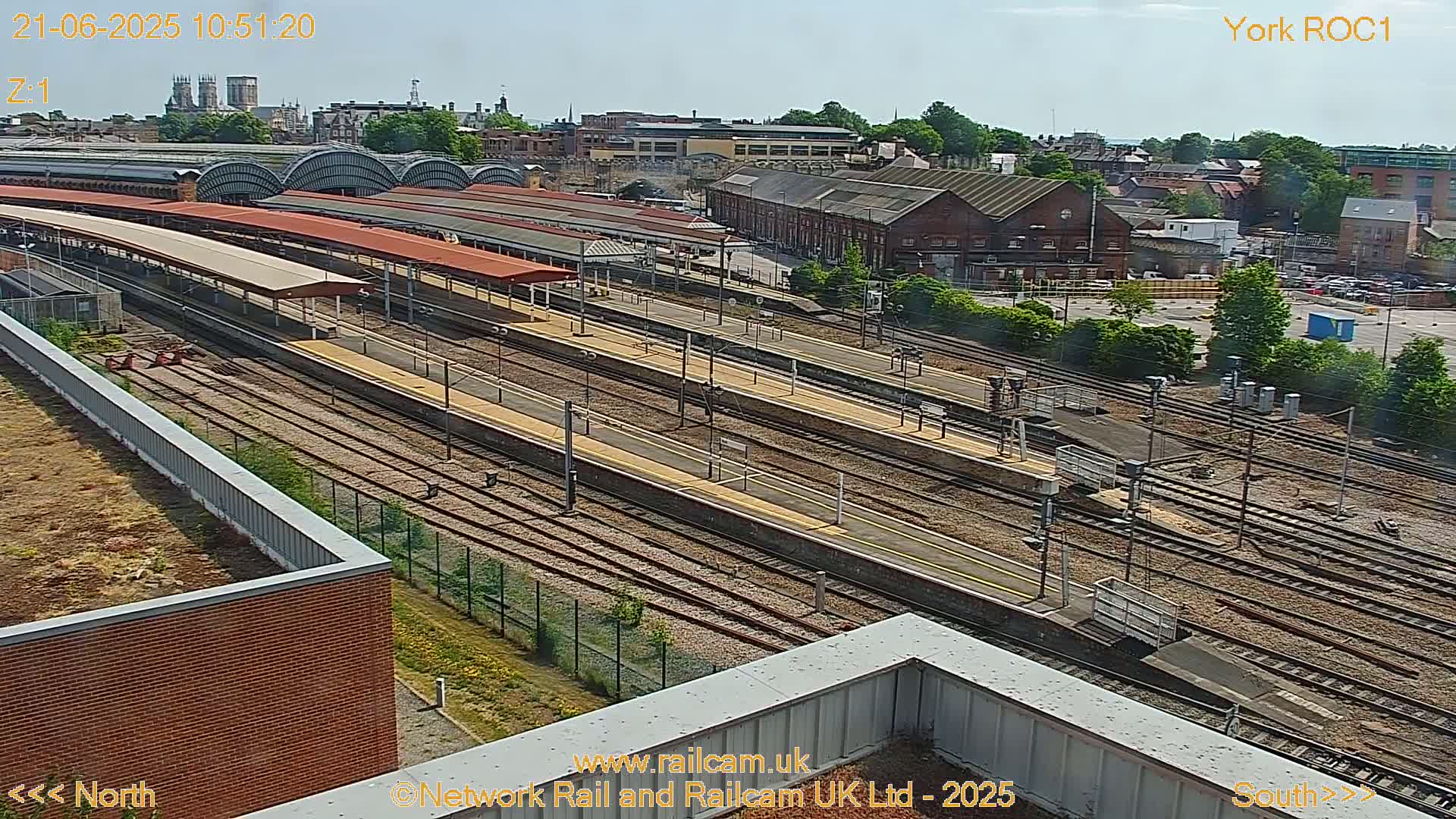 A high-angle view of a railway station and its tracks on a sunny day.