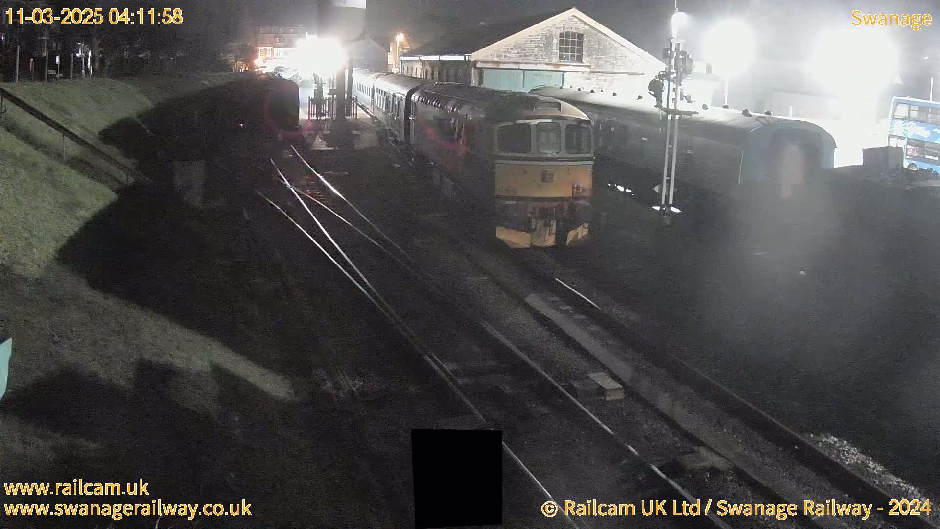 A diesel train is departing a station at night.