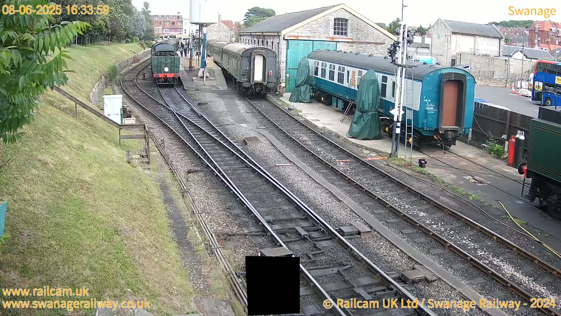 Several railway carriages and locomotives are parked on multiple railway tracks at a station on an overcast day.