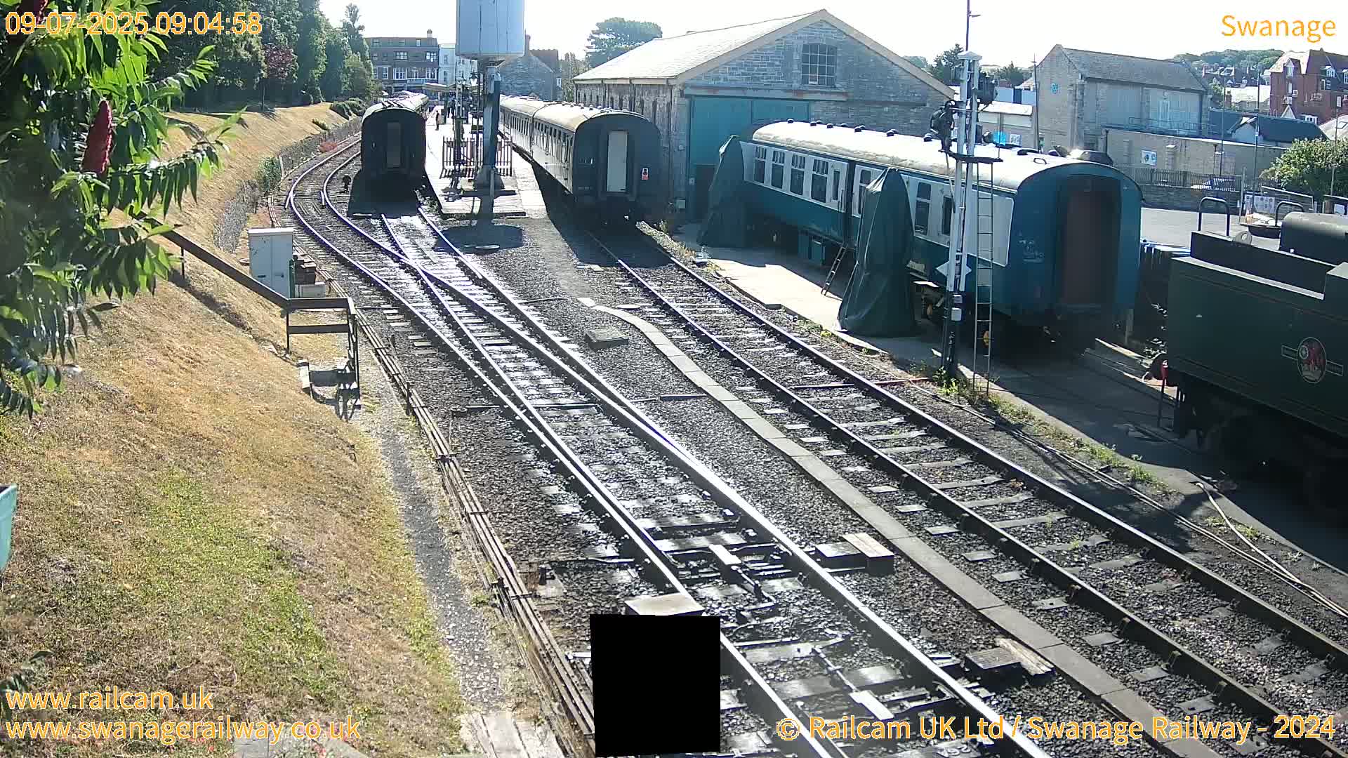Several railway carriages and a locomotive are parked on train tracks on a sunny day.