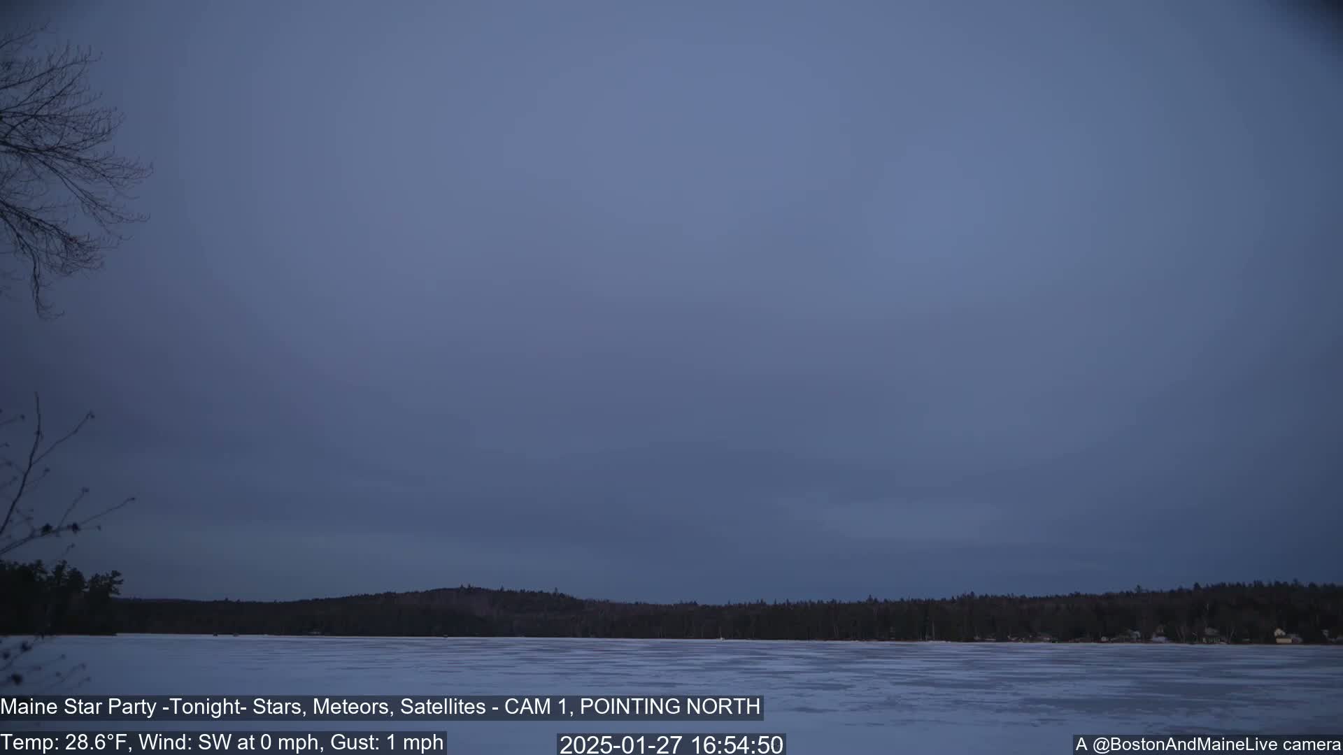 A frozen lake is visible under a dusky, twilight sky with calm, light winds.
