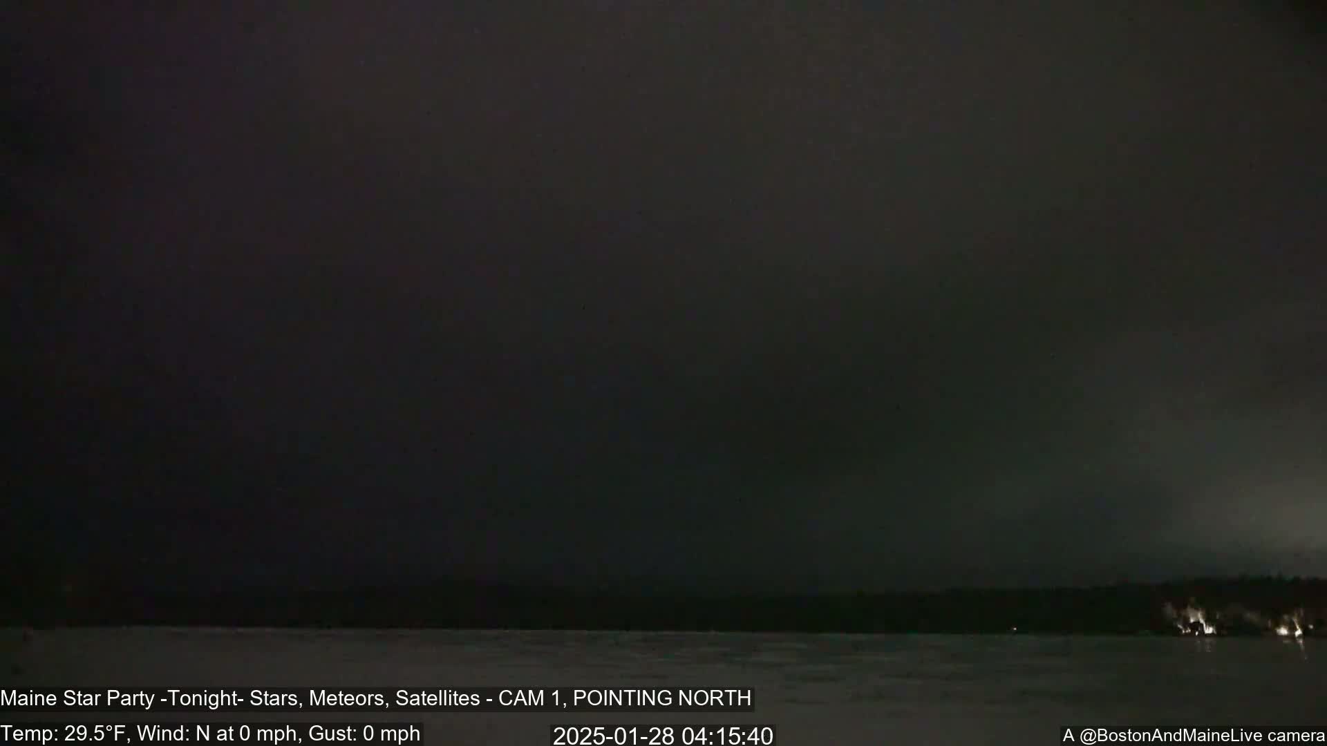 A dark, nighttime scene shows a calm body of water under a mostly clear, dark sky.