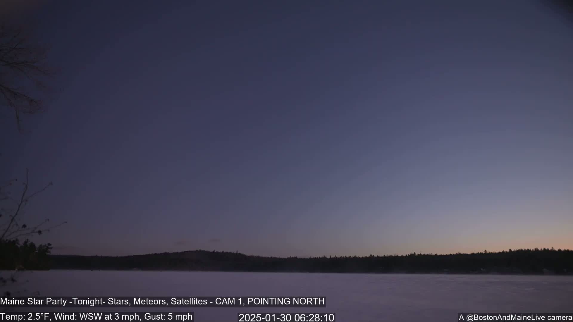 A twilight sky over a frozen lake with a dark treeline in the background, under a calm, cold sky.